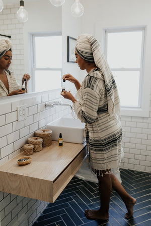 Woman wearing the Ribbon Turkish Towel as a head wrap while applying skin care