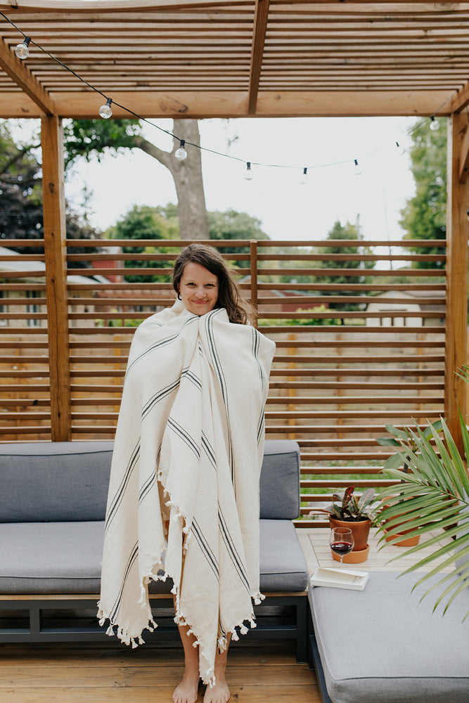 
            
                Load image into Gallery viewer, Woman wrapped in the Ribbon Stripe Blanket in Pearl
            
        