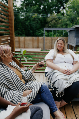 Woman sitting on the patio using the Stripe Turkish Towel as a shawl