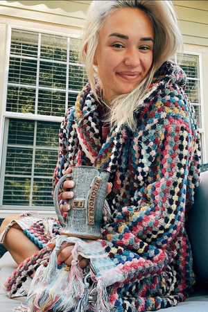 Woman drinking coffee in her Rainbow Pom Pom Bathrobe